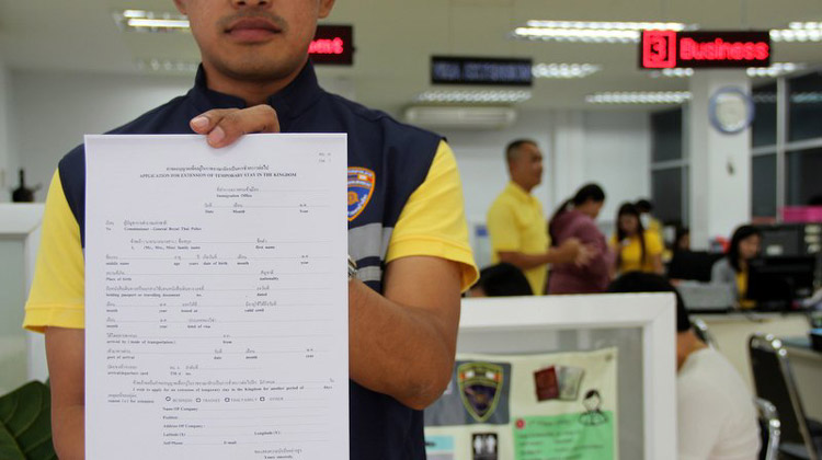 Keine Krankenversicherungspflicht - Beamter der Phuket Immigration zeigt Antragsformular